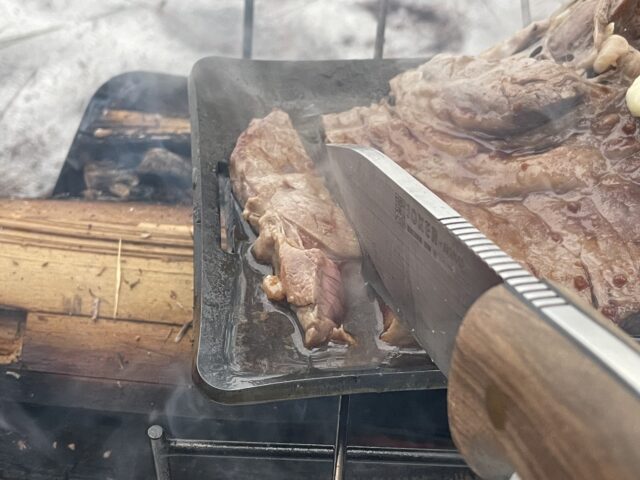 ヒロシ鉄板で焼いた肉を切る